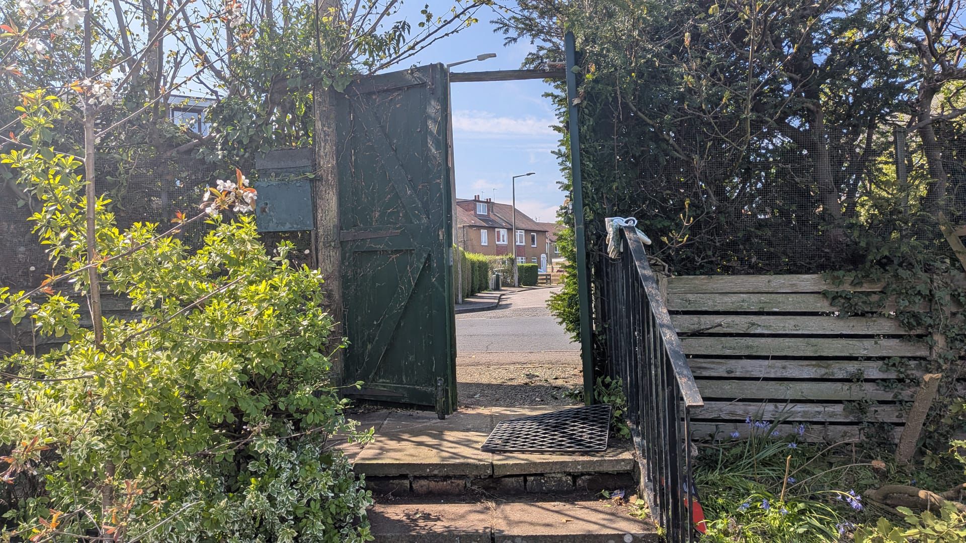 An open gate leading from a greenspace onto a street in Oxgangs, Edinburgh.
