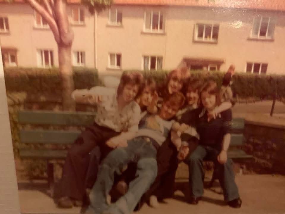A group of young men in 1970s hairstyles and clothing on a bench in Oxgangs